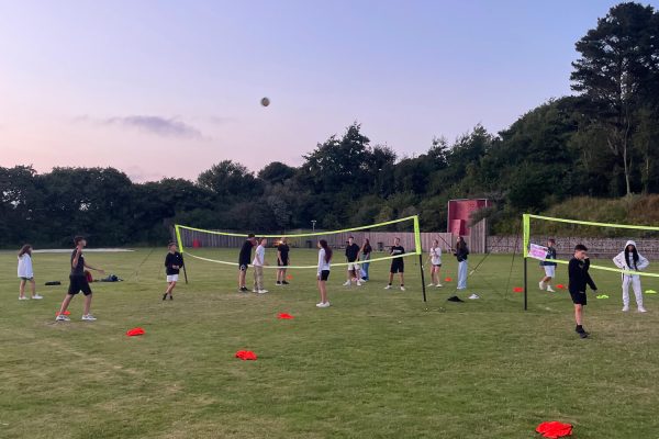 Junior Summer School students playing volleyball in the evening.